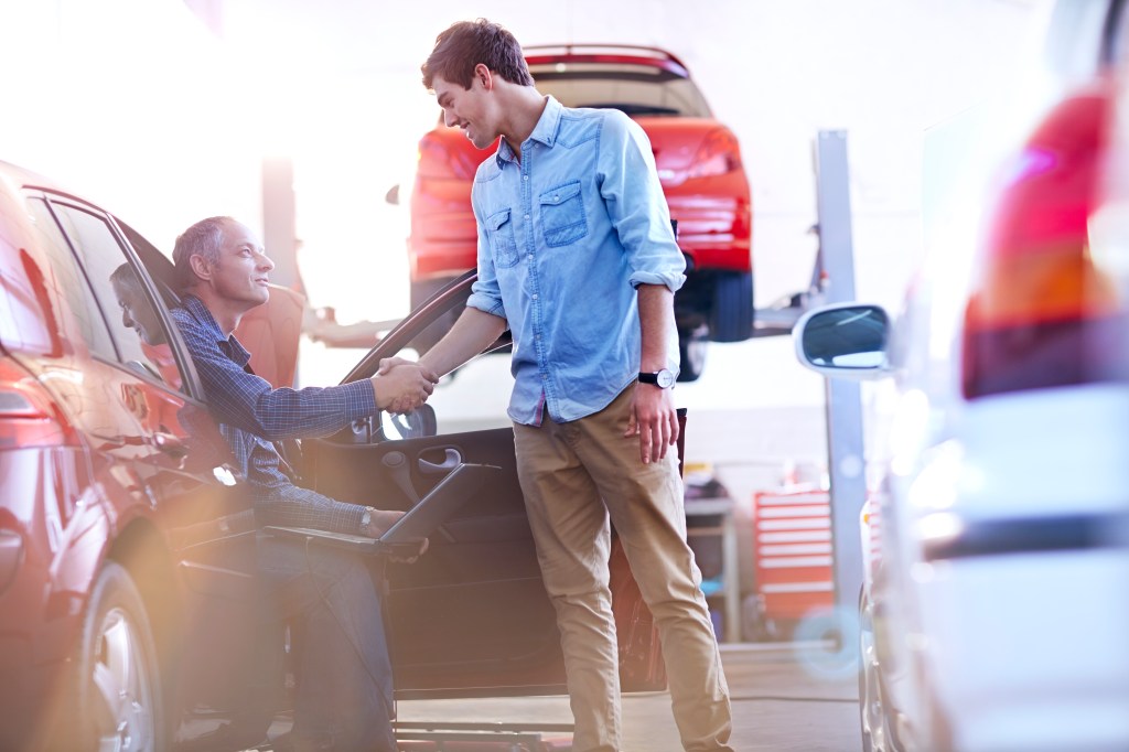 Mechanic and customer handshaking in auto repair shop